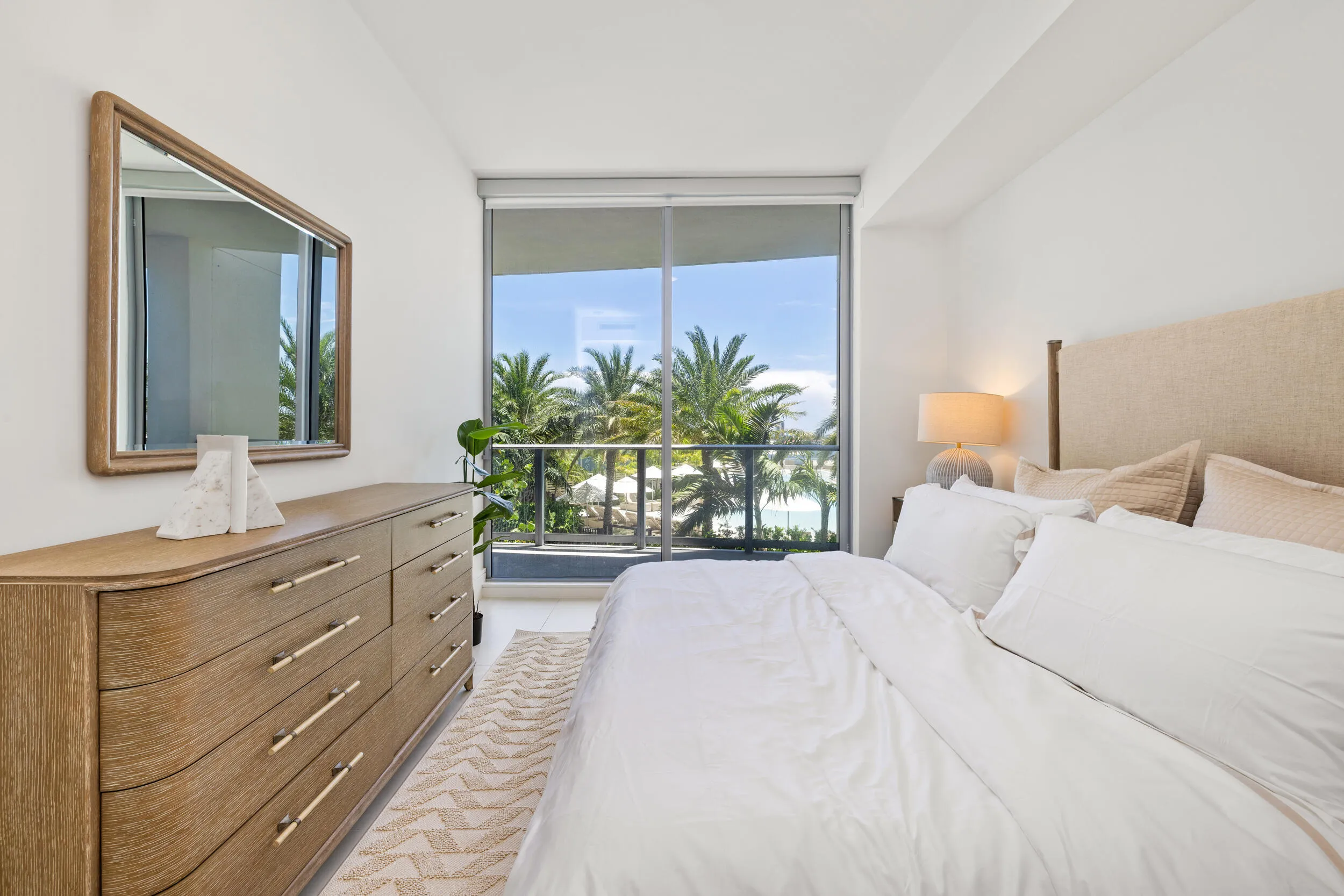 Floor-to-ceiling windows, outdoor balcony, water element, and lush tropical landscaping