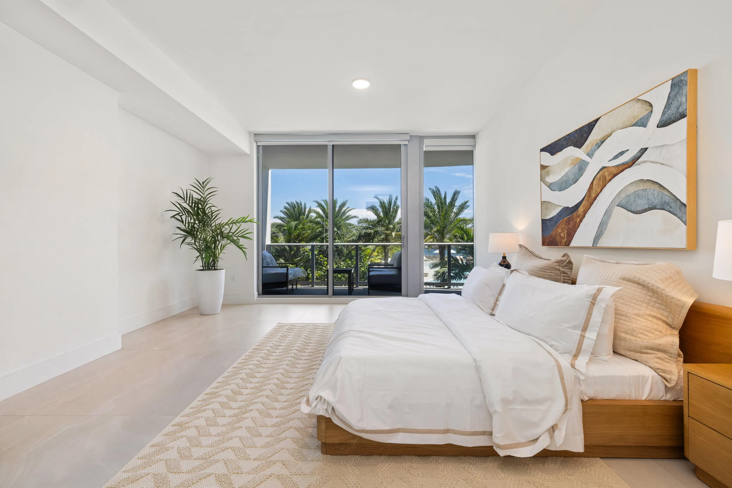 Recessed lighting throughout, floor-to-ceiling sliding glass doors, balcony access, and light-toned tile flooring