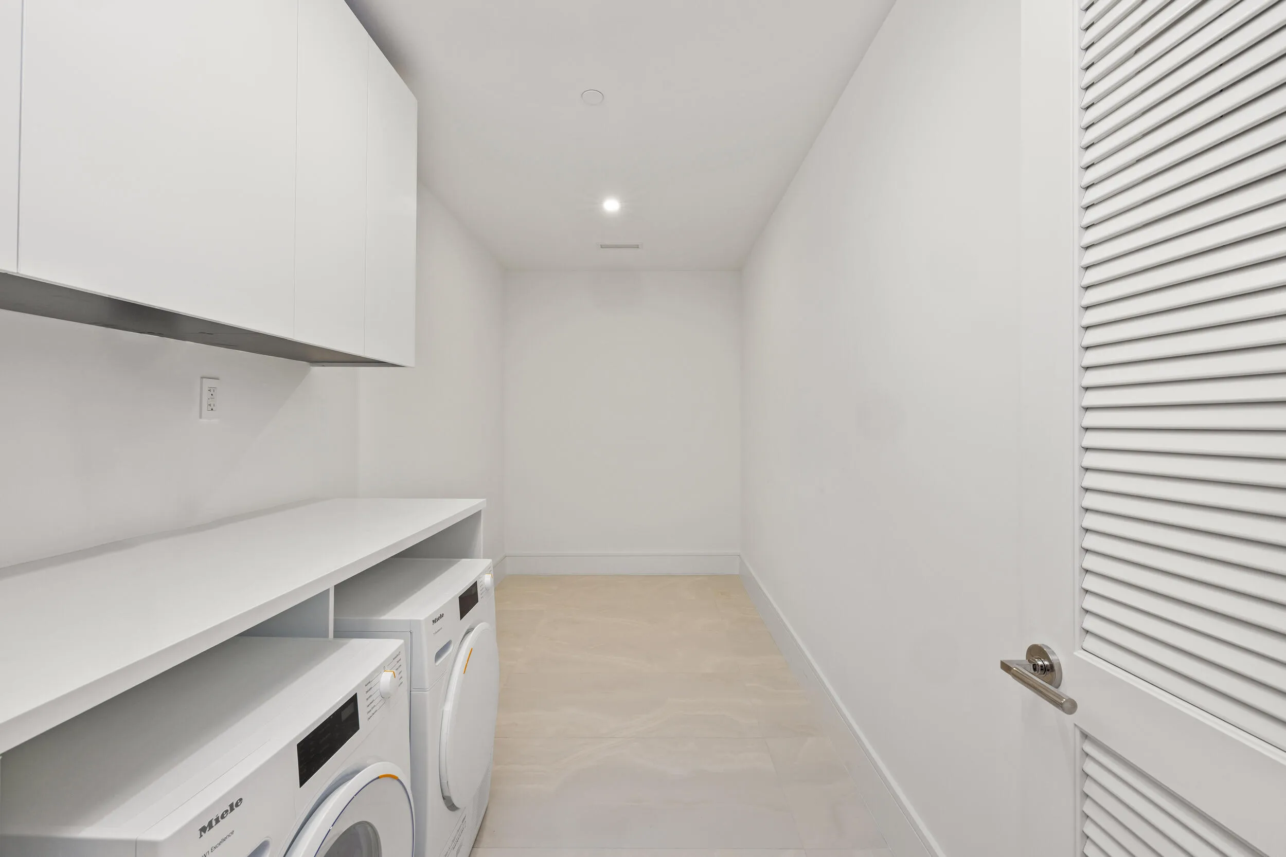 Large Laundry area featuring recessed lighting, a built-in countertop, white upper cabinetry, and light-toned flooring