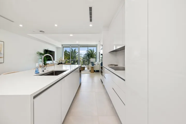 Gourmet kitchen featuring a waterfall island, integrated sink, flat-panel cabinetry, and recessed lighting