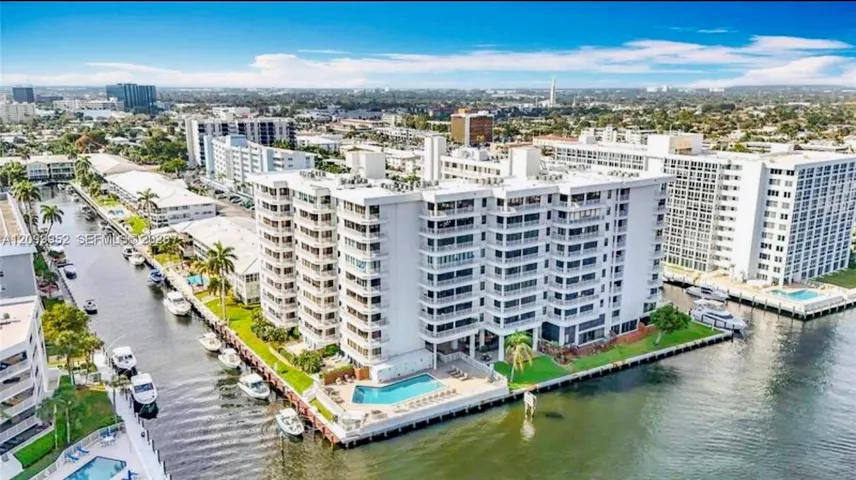 Waterfront high-rise building featuring private balconies, an exterior swimming pool, concrete seawall, and deep-water canal access