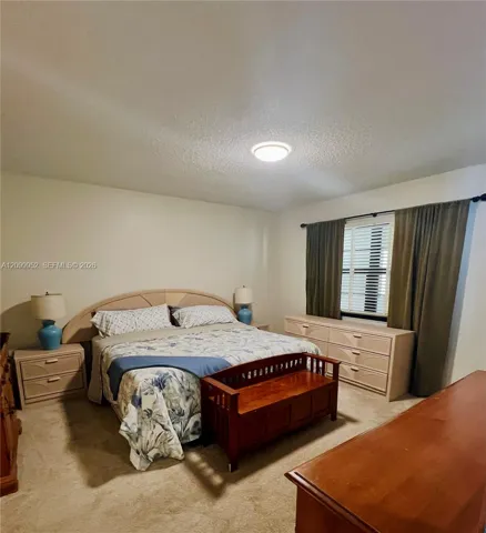 Neutral-toned interior space featuring wall-to-wall carpeting and a window with horizontal blinds