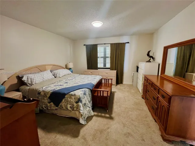 Neutral-toned walls, wall-to-wall carpeting, and a single window featuring grid muntins