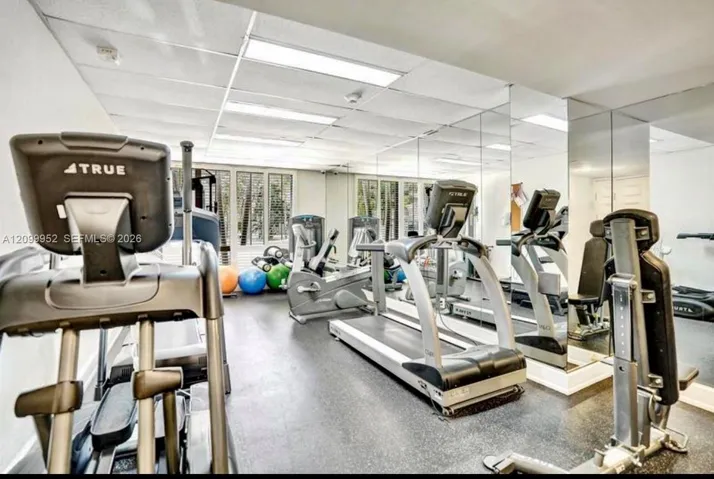 Full-wall mirrored surfacing, drop ceiling with recessed lighting, and durable rubberized flooring