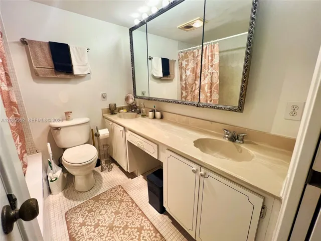 Extended vanity with dual integrated sinks, solid-surface countertop, expansive tri-fold medicine cabinet, and tiled flooring