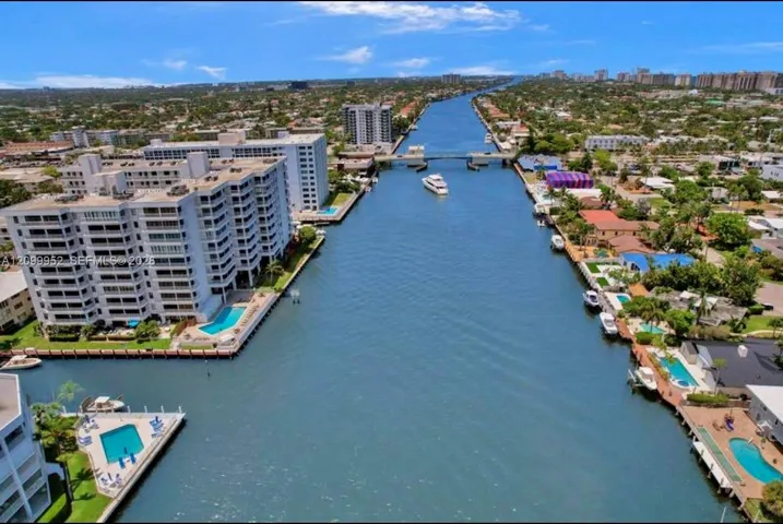 Aerial perspective of a deep-water canal featuring residential waterfront properties, private swimming pools, and bulkheaded seawalls