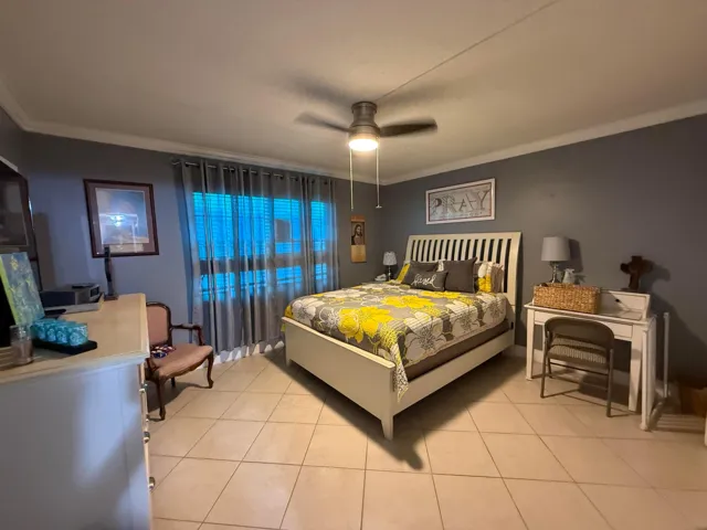 Tiled flooring, ceiling fan with integrated lighting, window with horizontal blinds, and crown molding