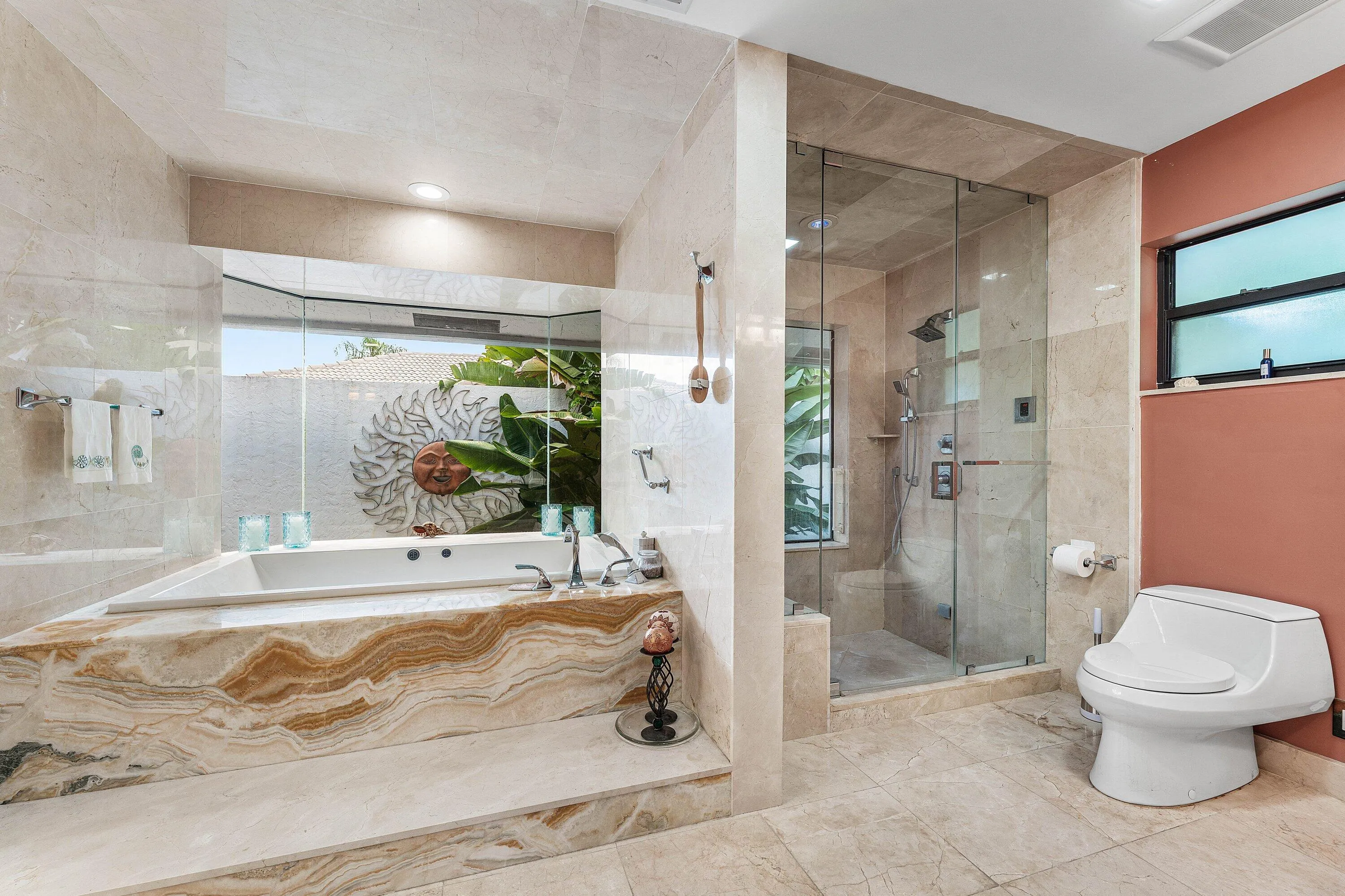Soaking tub with a natural stone surround, a walk-in shower with a glass enclosure, and a wall-mounted toilet