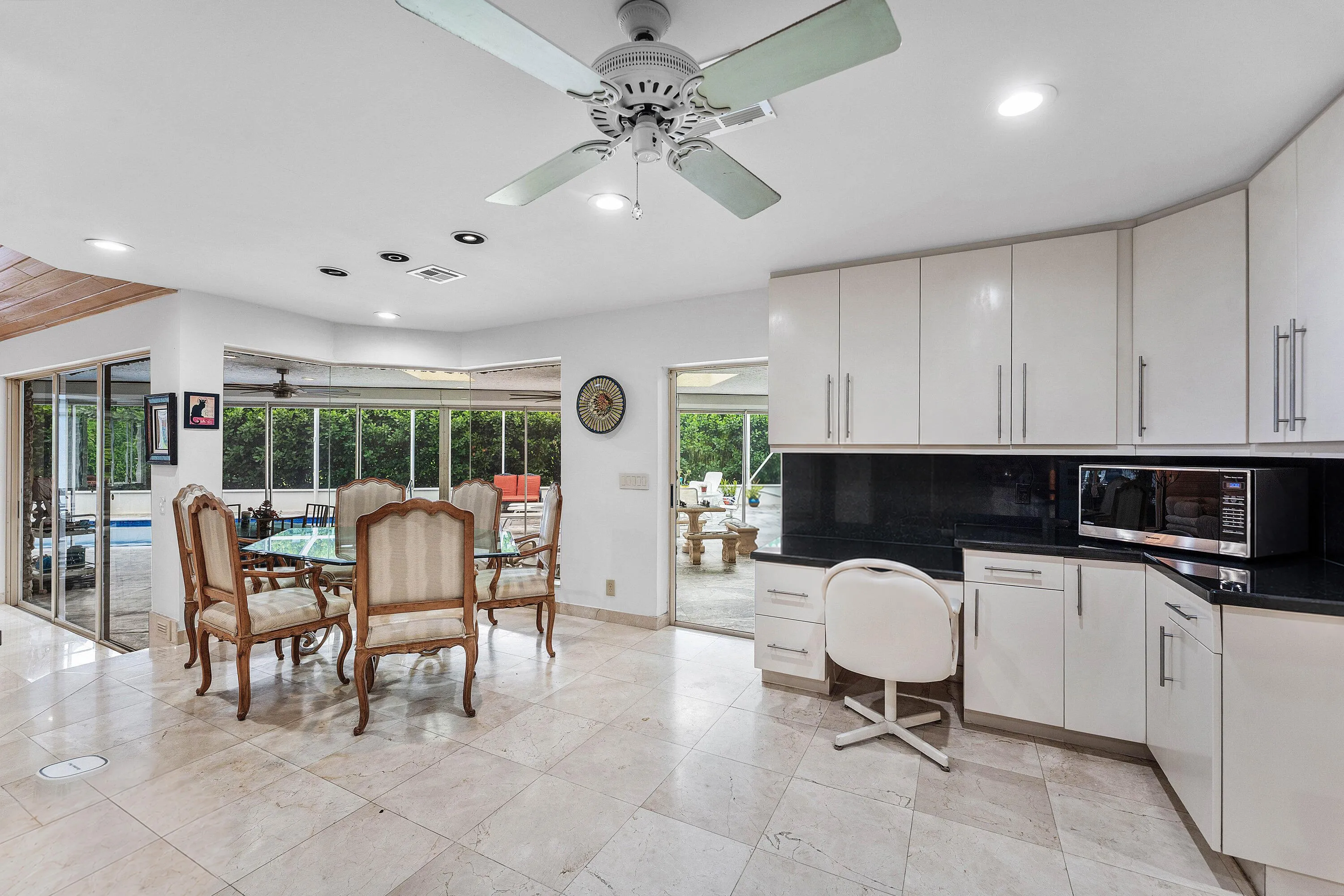 Polished tile flooring throughout, white cabinetry with dark countertops, recessed lighting, and expansive glass sliding doors