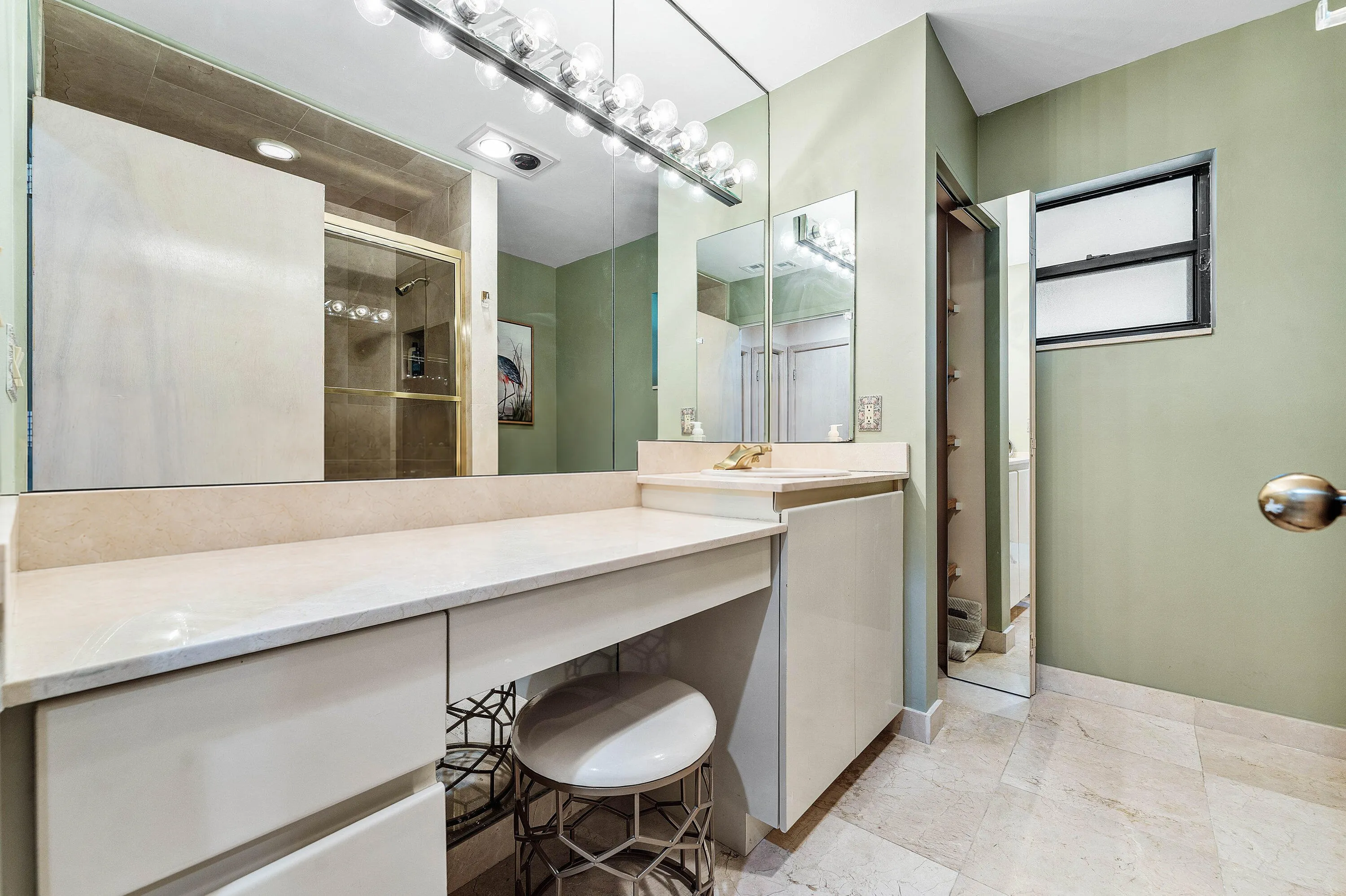 Built-in vanity with light-toned countertop, integrated cabinetry, and full-width mirror