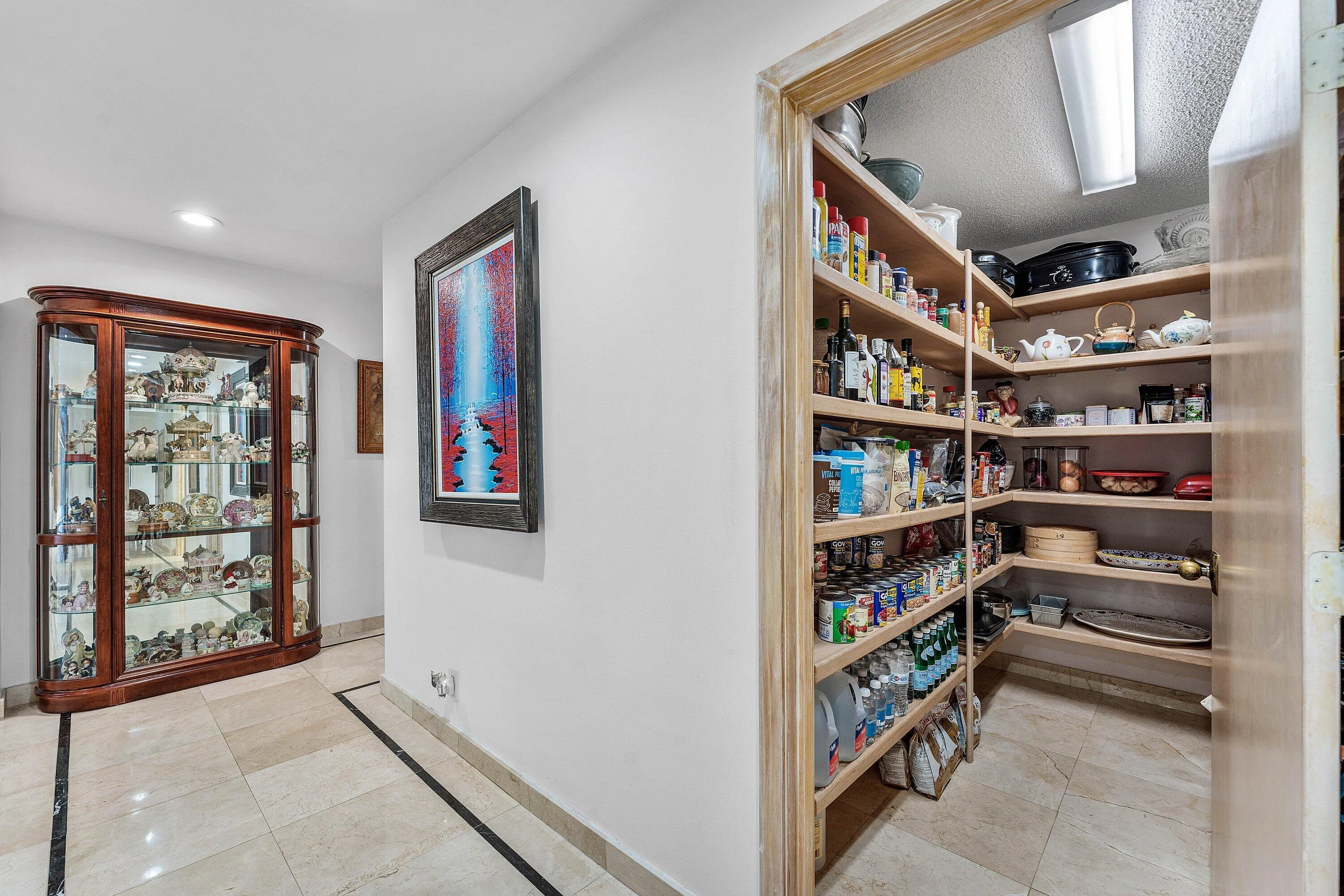 Spacious pantry featuring extensive wood shelving, integrated lighting, and tile flooring
