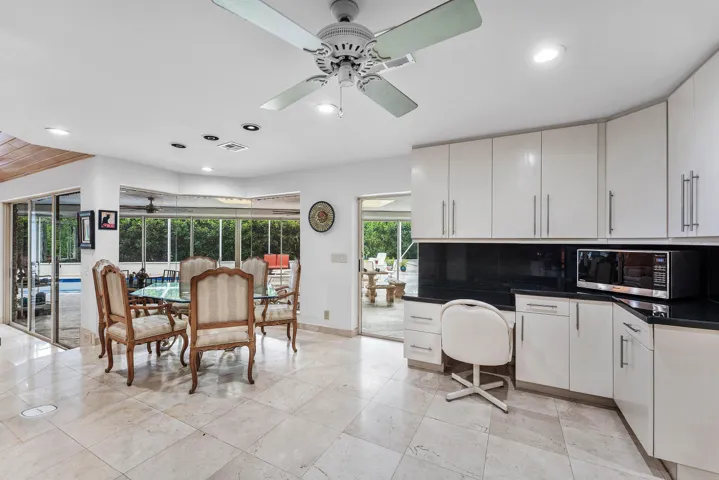 Polished tile flooring throughout, white cabinetry with dark countertops, recessed lighting, and expansive glass sliding doors