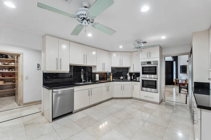 Kitchen featuring extensive cabinetry, stainless steel appliances, black countertops, and a built-in pantry
