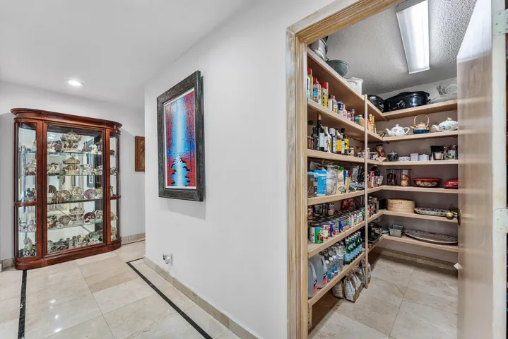 Spacious pantry featuring extensive wood shelving, integrated lighting, and tile flooring