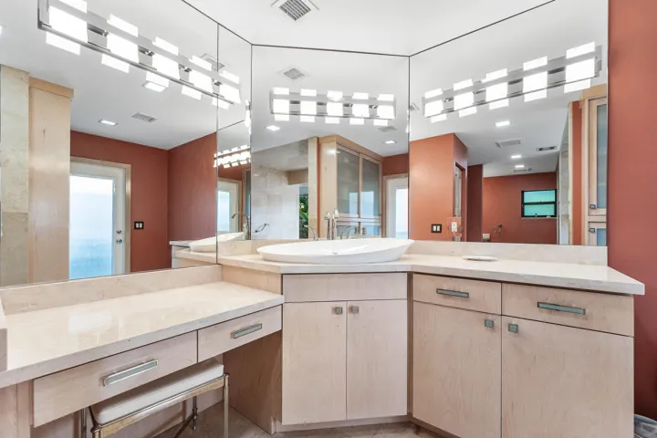 Dual vanity with light wood-finish cabinetry, integrated vessel sink, and an expansive countertop