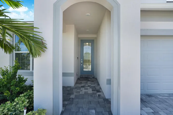 A nice covered entry way leading to a glass-panel door that allows natural light to flow into the foyer