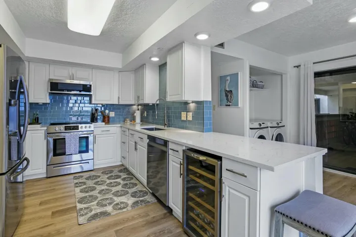 Beautifully updated kitchen with space for seating stools and opens to an in unit laundry area for easy access
