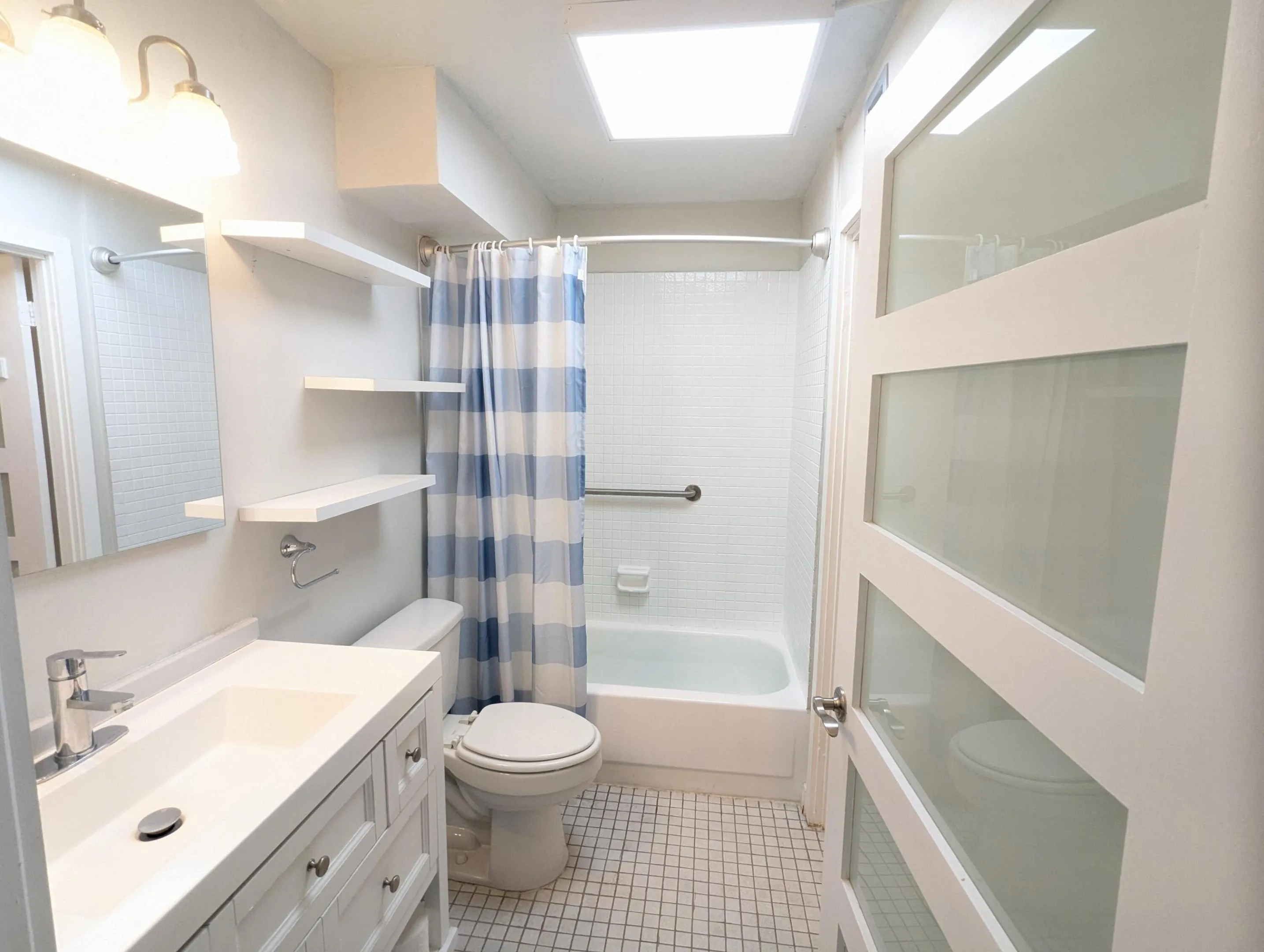 Primary bath white vanity with integrated sink, chrome faucet, and tiled flooring