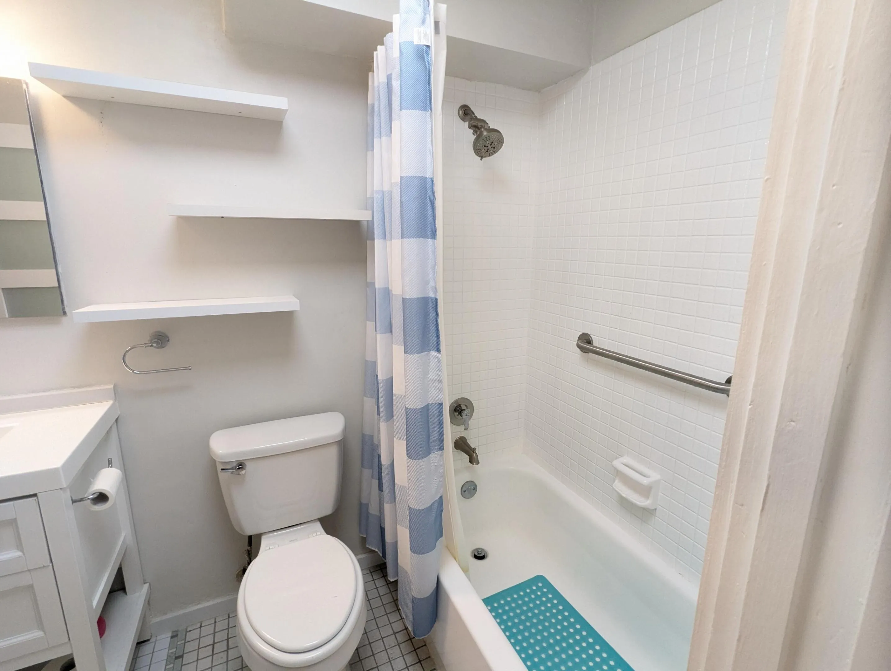 Floating wall shelves, a built-in bathtub, and white subway tile surround