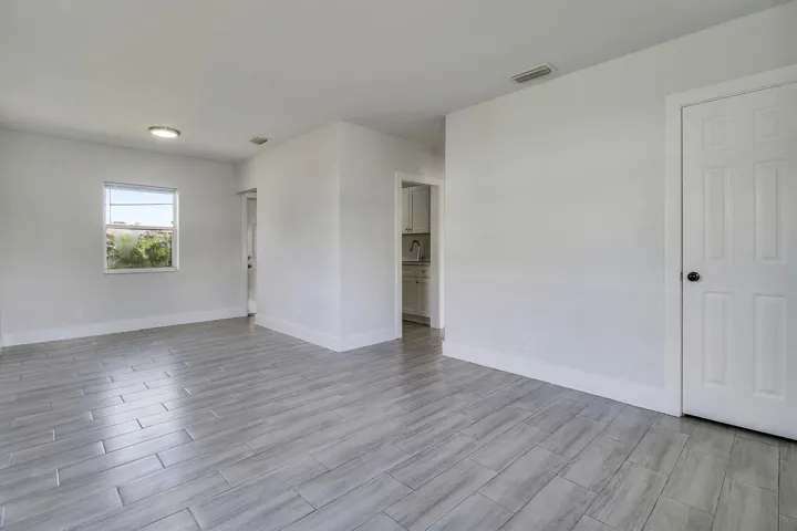 Spacious room with light gray plank-style tile flooring, white walls, and a window
