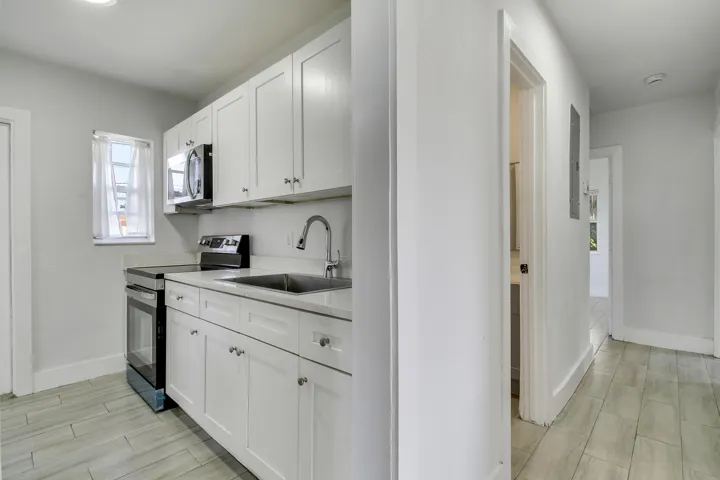 Kitchen featuring white cabinetry, stainless steel sink, and light-toned countertops