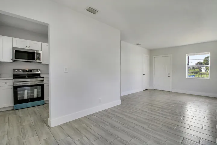Open-concept living space with wood-finish tile flooring, white walls, and a large window