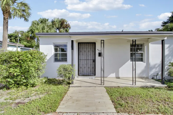 White stucco exterior with a covered porch featuring wrought iron columns