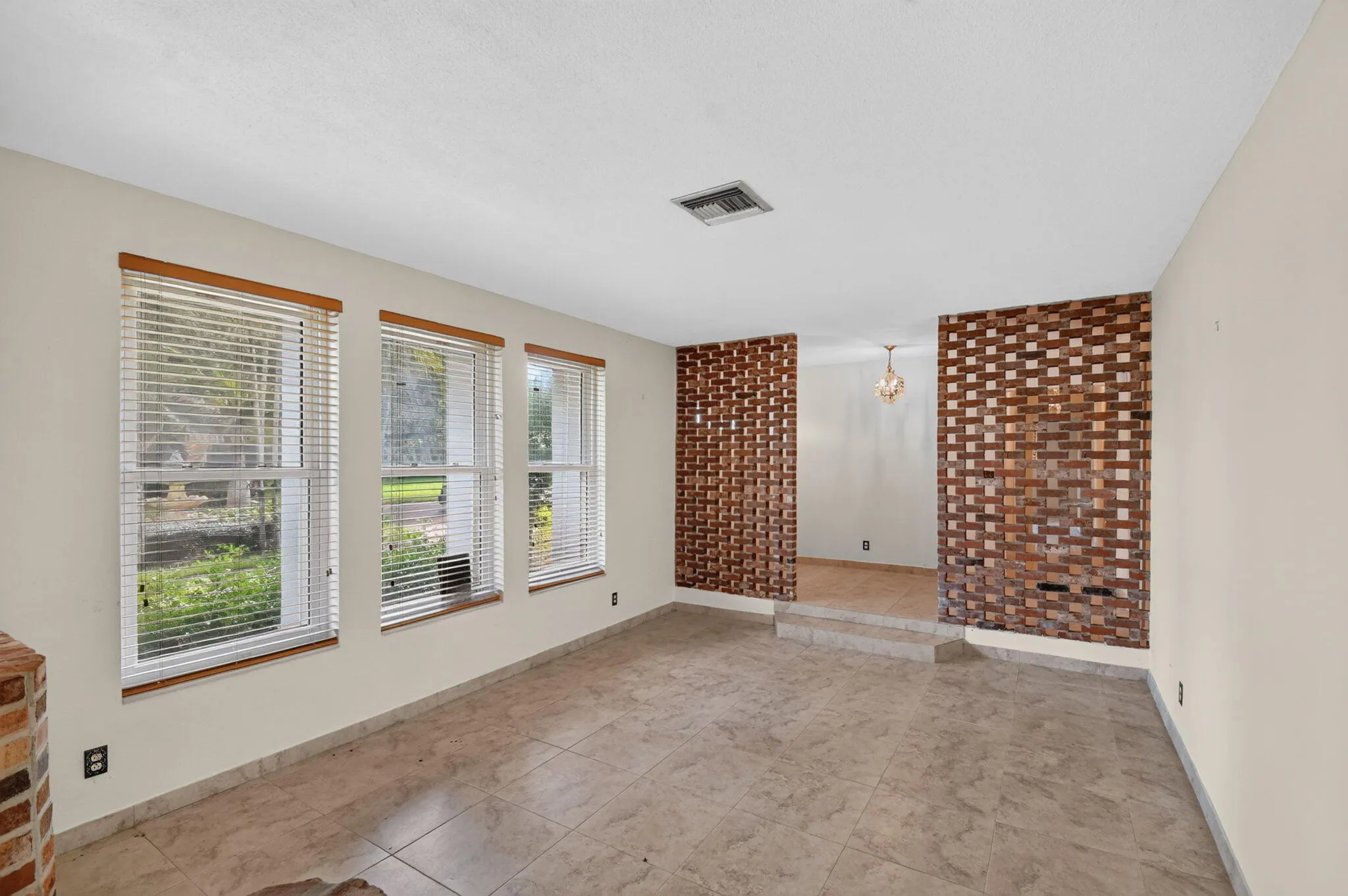 Tile flooring, white painted walls, exposed brick half-walls, recessed lighting, and multiple windows with blinds