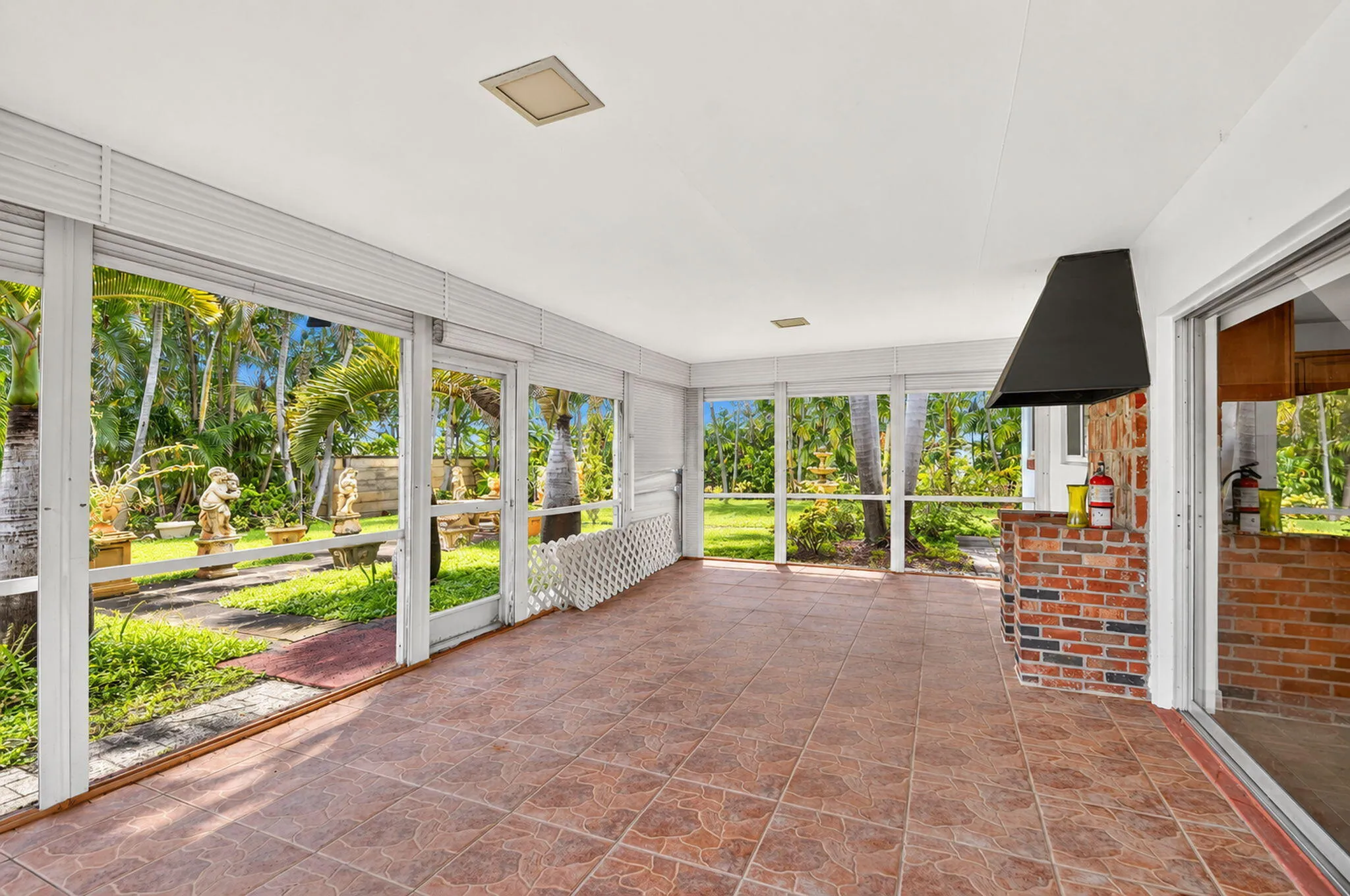 Screened enclosure with tile flooring, brick-faced built-in counter, and a permanent range hood