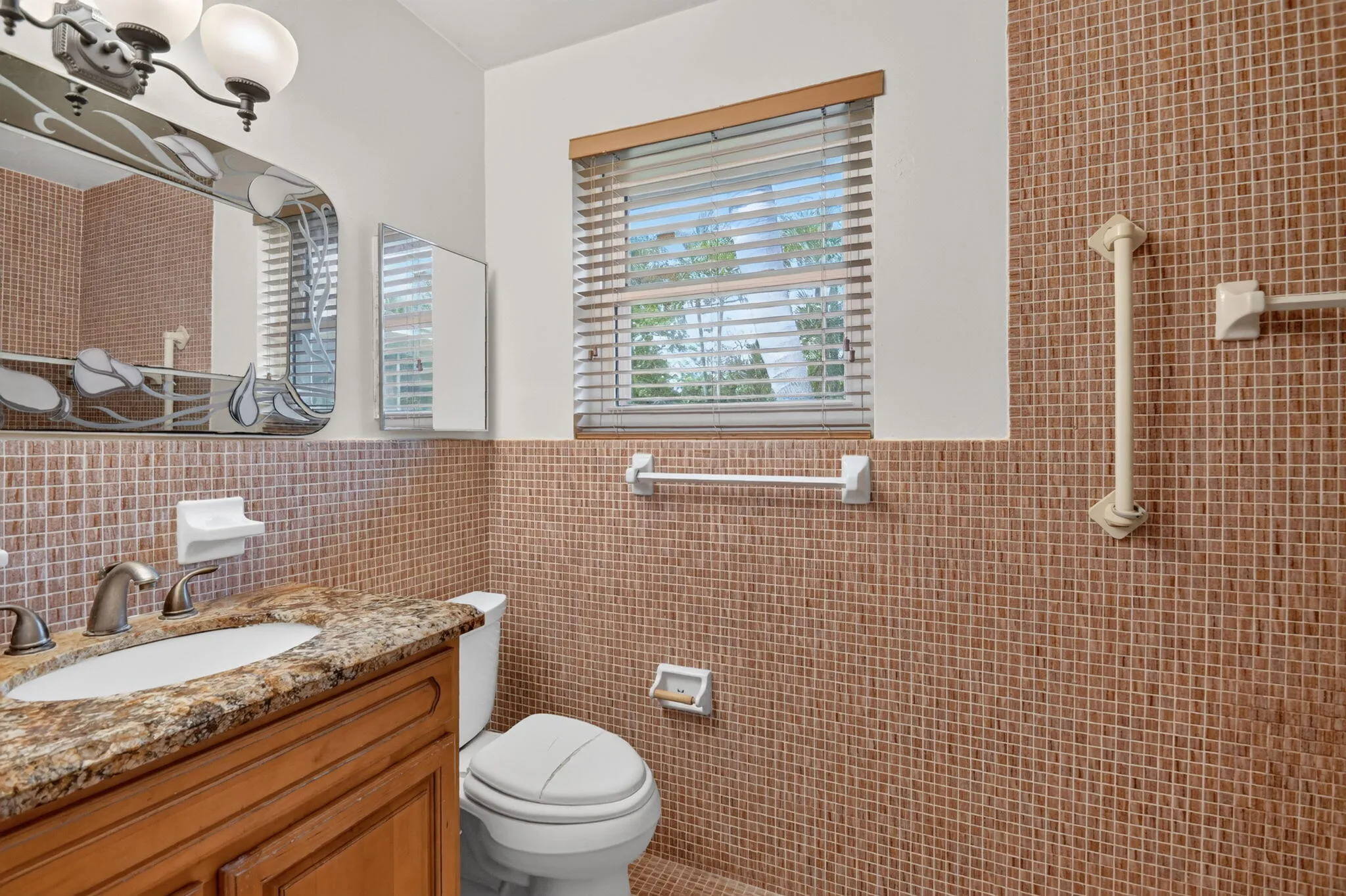Vanity with stone countertop, integrated sink, and wood-finish cabinetry