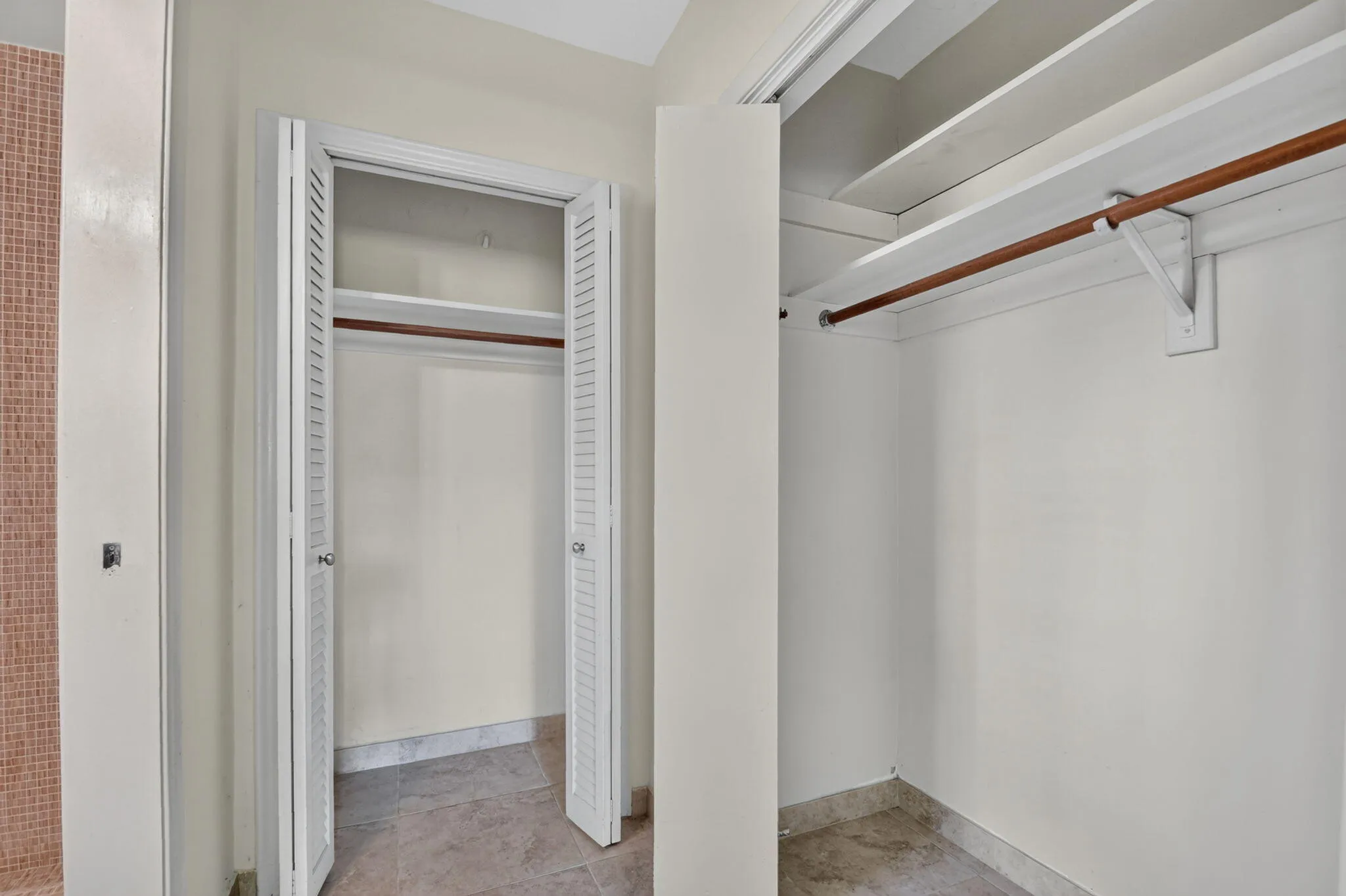 Dual closets with louvered bifold doors, featuring integrated shelving and clothing rods
