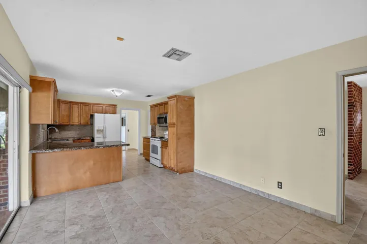 Kitchen featuring wooden cabinetry, white appliances, granite-style countertops, and tile flooring