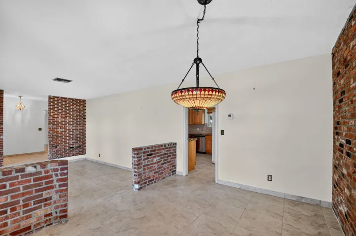 Exposed brick walls, tile flooring, and a decorative pendant light fixture. Take down the wall to create large open living area.