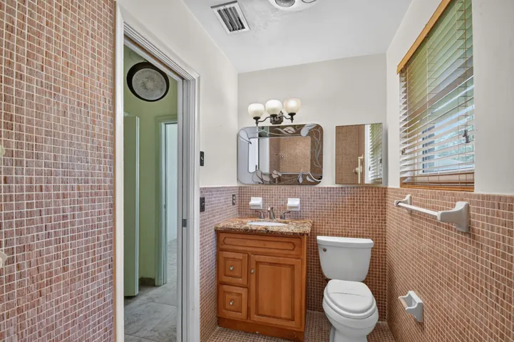 Vanity with a polished stone countertop, wood-finish cabinetry, and an integrated sink