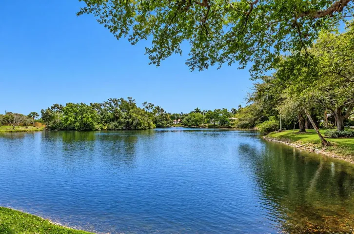 Lakeside setting featuring mature trees and lush green landscaping