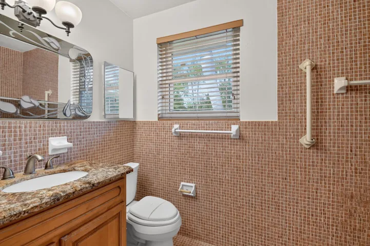 Vanity with stone countertop, integrated sink, and wood-finish cabinetry