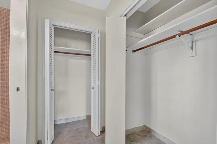 Dual closets with louvered bifold doors, featuring integrated shelving and clothing rods