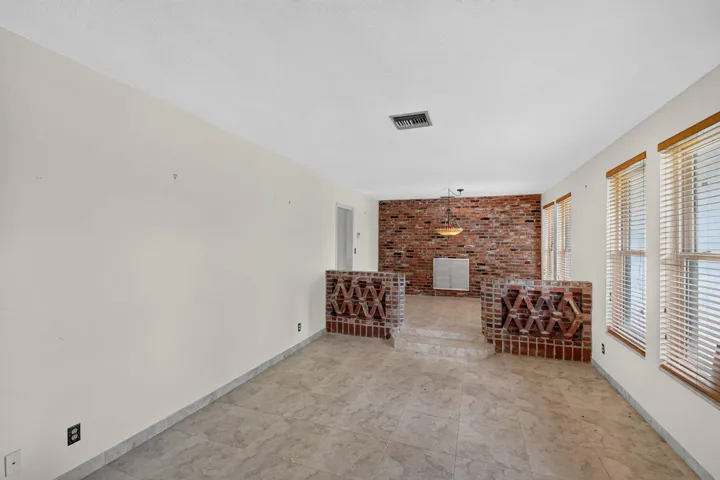 Spacious room with tile flooring, brick accent wall, and multiple windows
