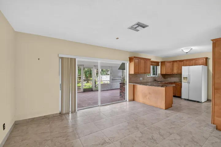 Kitchen with wood cabinetry, stone countertops, and tile flooring
