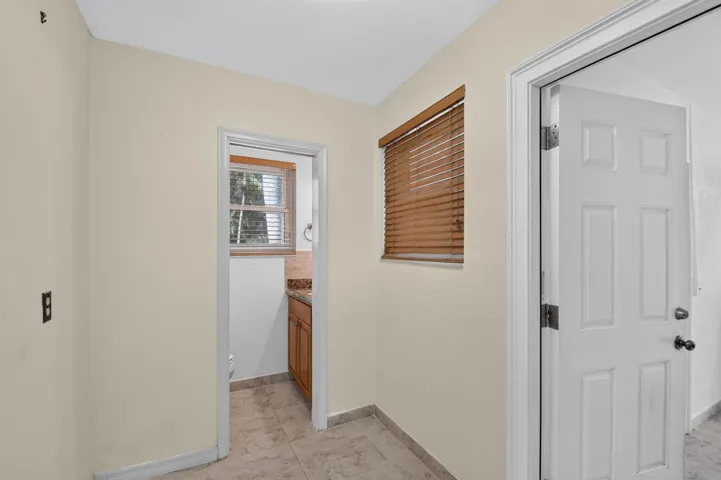 Tile flooring, neutral wall paint, wood window blinds, paneled interior doors, and a recessed doorway with an interior window