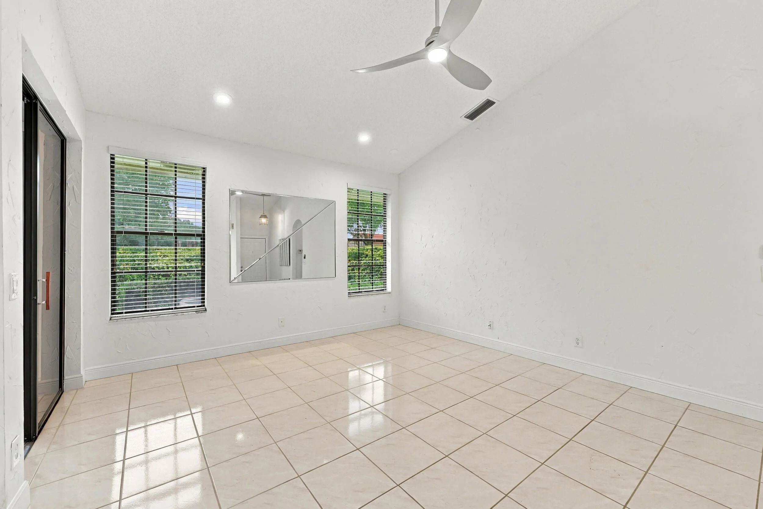 Vaulted ceiling with a ceiling fan and recessed lighting, tile flooring, and two windows with blinds
