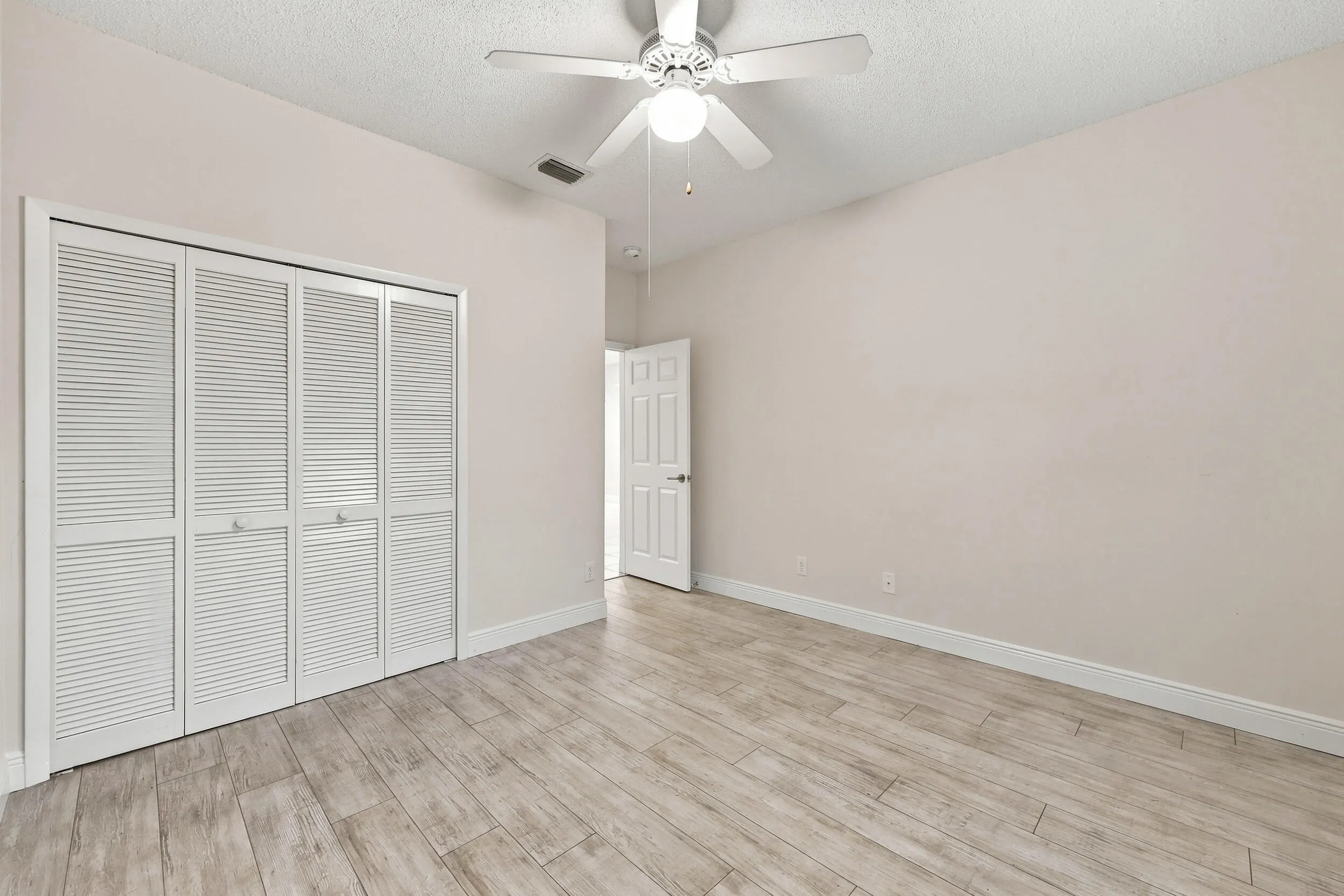 Wood-finish flooring throughout, complemented by a white ceiling fan with integrated lighting
