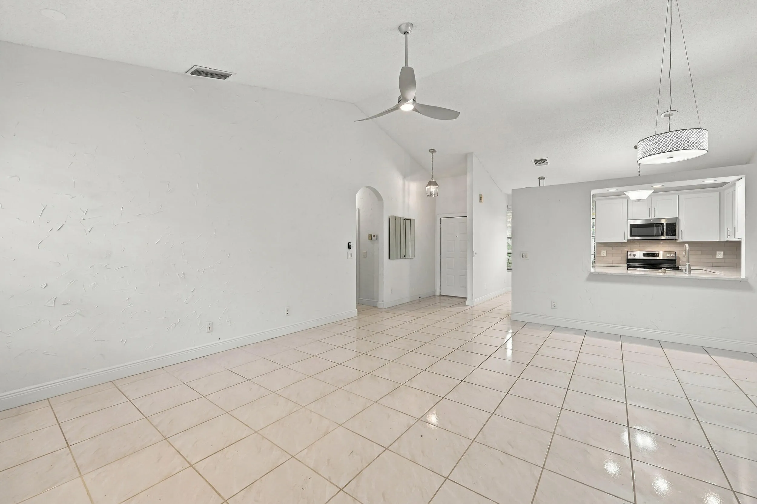 Vaulted ceilings, tiled flooring, arched doorway, and recessed kitchen pass-through