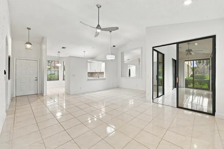 Spacious interior featuring vaulted ceilings, large format tile flooring, and multiple ceiling fans
