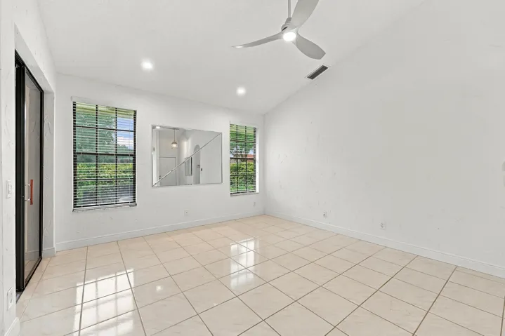 Vaulted ceiling with a ceiling fan and recessed lighting, tile flooring, and two windows with blinds