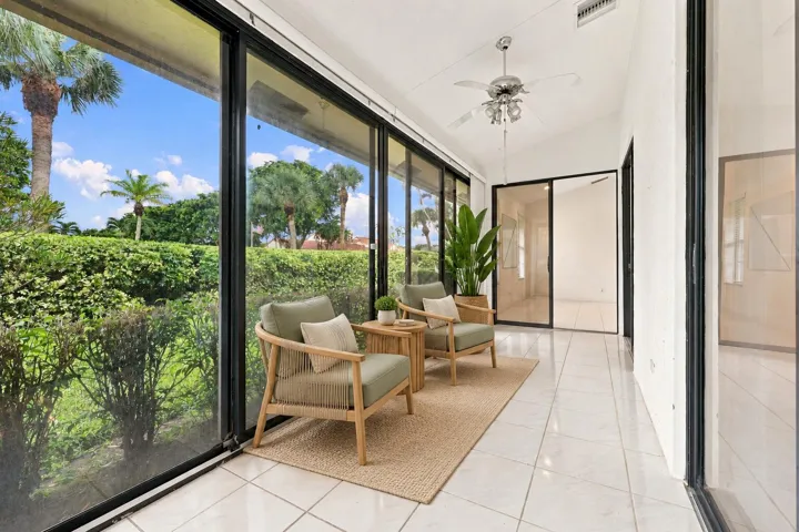 Expansive room featuring floor-to-ceiling sliding glass doors, a vaulted ceiling, and a ceiling fan