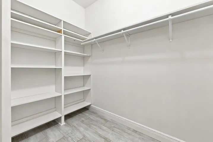Built-in shelving and hanging rods with wood-finish flooring