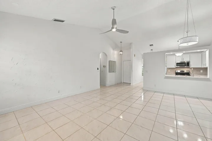 Vaulted ceilings, tiled flooring, arched doorway, and recessed kitchen pass-through