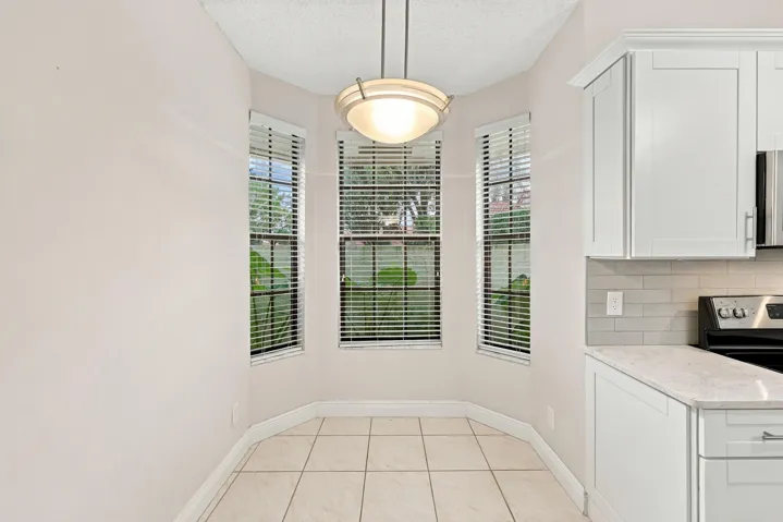 Bay window area with tile flooring, featuring a contemporary pendant light fixture, white cabinetry, and a light-toned countertop