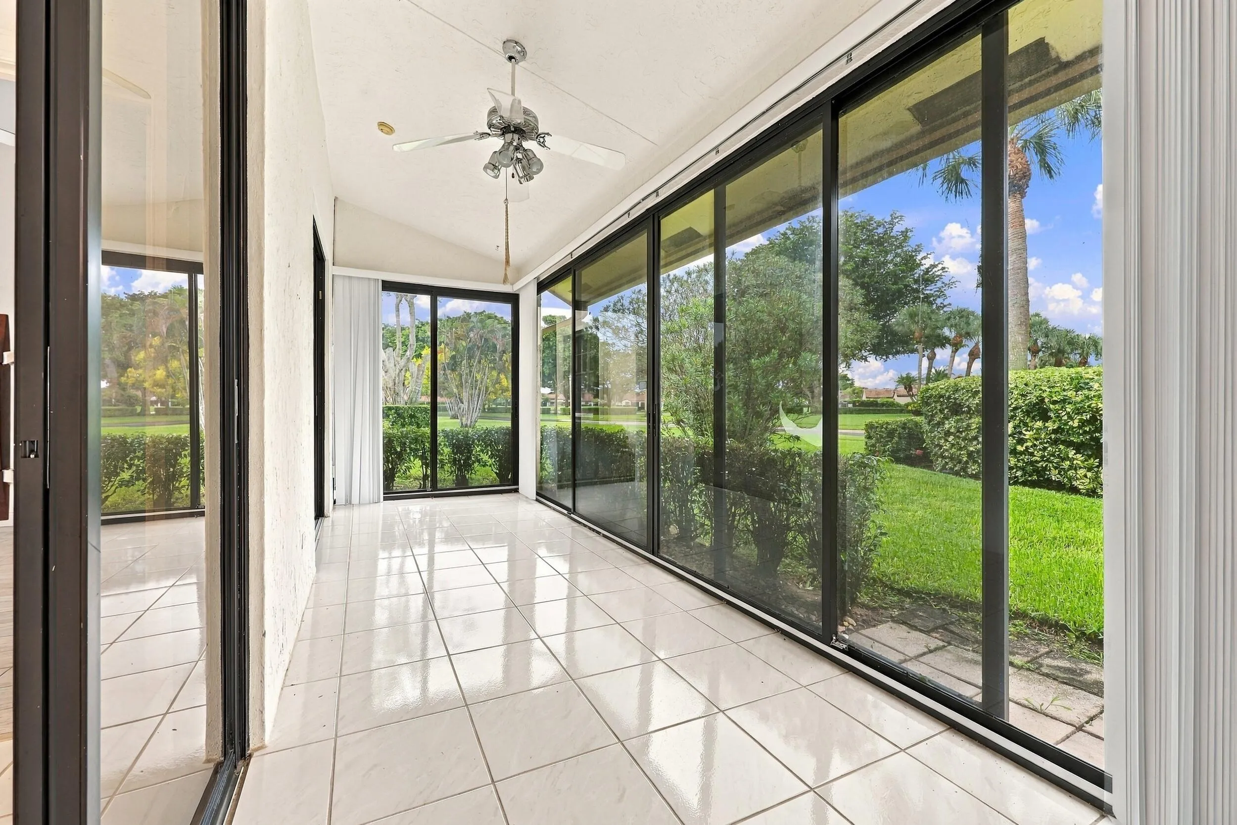 Enclosed patio featuring white tile flooring, a vaulted ceiling, and a ceiling fan